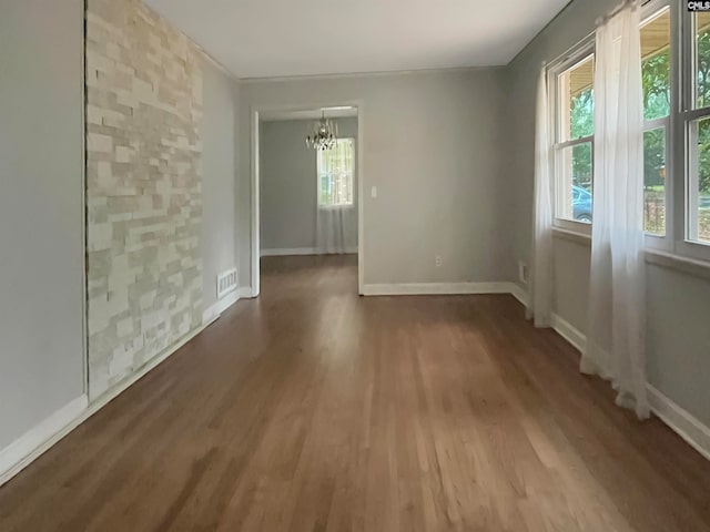 empty room with hardwood / wood-style floors and an inviting chandelier