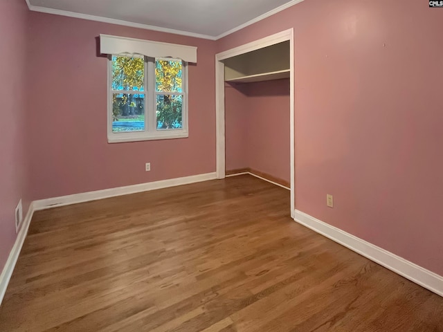 unfurnished bedroom featuring a closet, ornamental molding, and hardwood / wood-style flooring