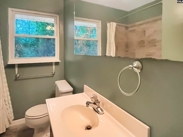 bathroom with walk in shower, vanity, and toilet