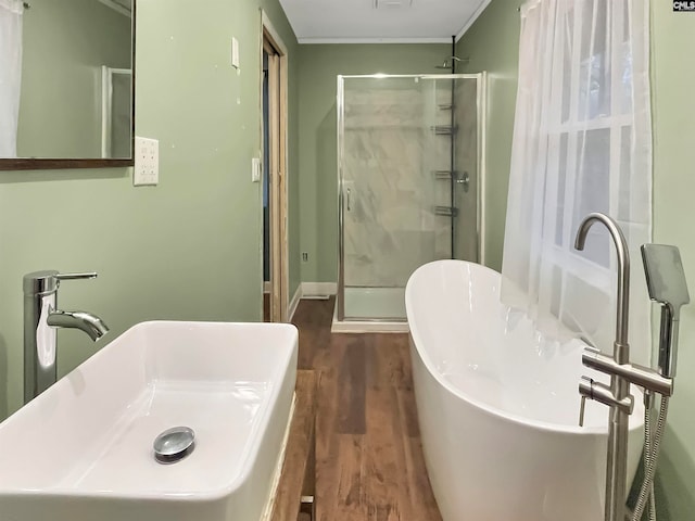 bathroom with plus walk in shower, hardwood / wood-style flooring, and sink