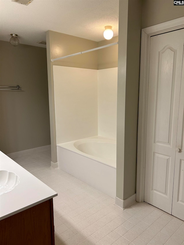 bathroom featuring tile patterned floors, a washtub, vanity, and a textured ceiling