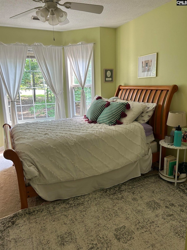 carpeted bedroom with ceiling fan and a textured ceiling