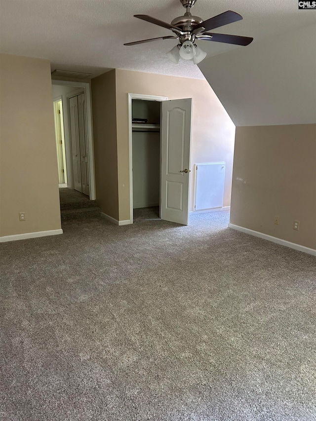 unfurnished bedroom featuring a textured ceiling, ceiling fan, carpet, and vaulted ceiling