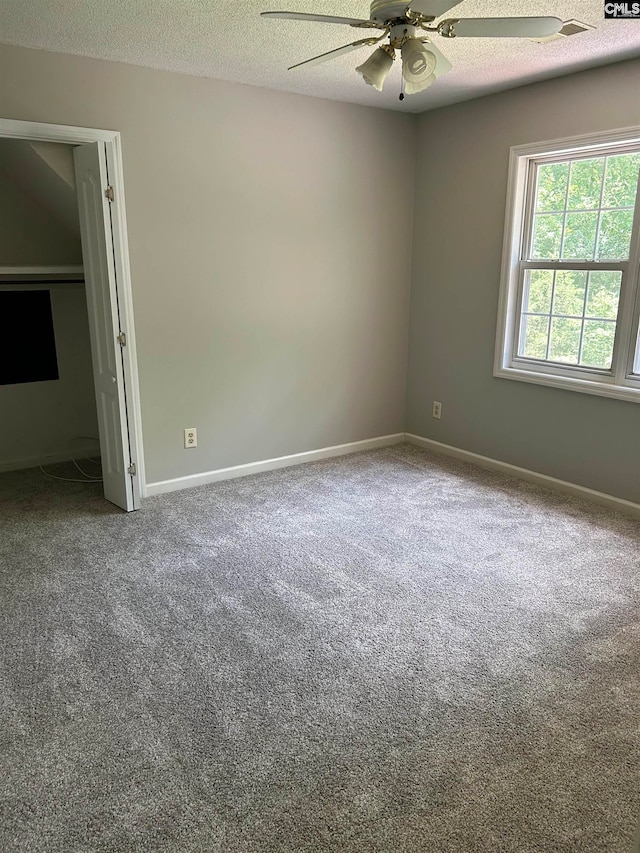 carpeted empty room with ceiling fan and a textured ceiling