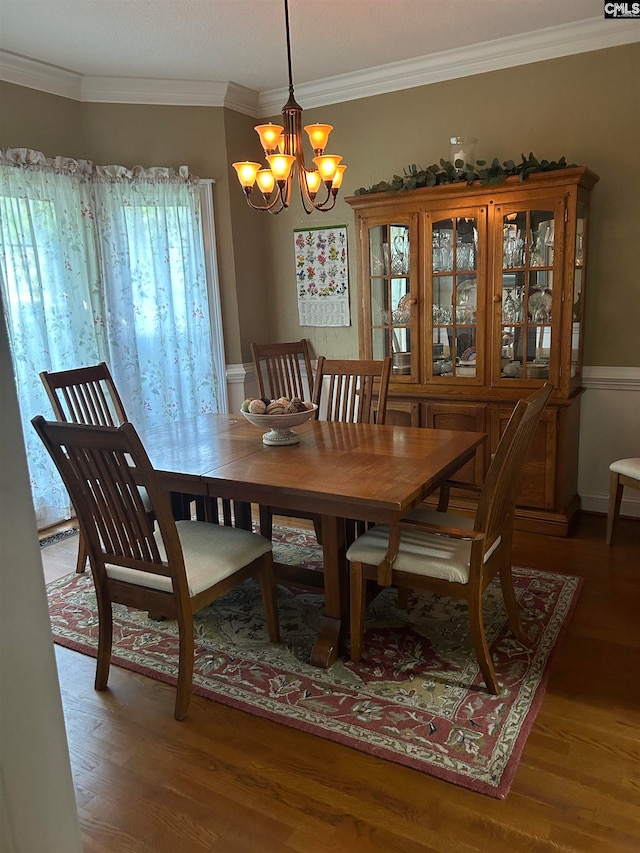 dining area with hardwood / wood-style flooring, crown molding, and a notable chandelier