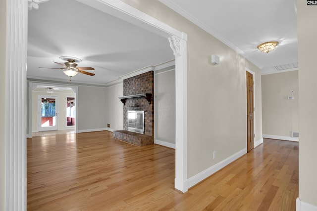 unfurnished living room with a brick fireplace, ceiling fan, ornamental molding, and light hardwood / wood-style flooring