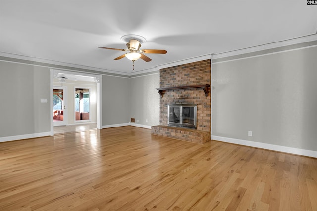 unfurnished living room featuring ceiling fan, light wood-type flooring, crown molding, and a brick fireplace