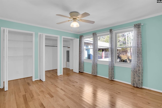 unfurnished bedroom with ceiling fan, light wood-type flooring, crown molding, and two closets