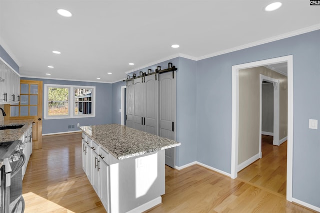 kitchen featuring white cabinetry, sink, light stone counters, and stainless steel range oven