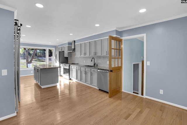 kitchen featuring wall chimney exhaust hood, light hardwood / wood-style floors, stainless steel appliances, gray cabinets, and a kitchen island