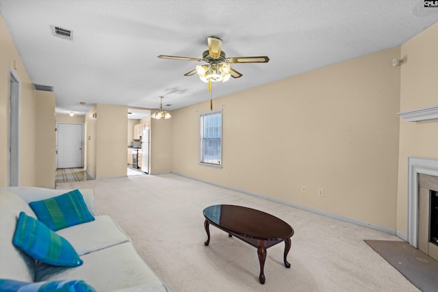 carpeted living room featuring a textured ceiling, a premium fireplace, and ceiling fan with notable chandelier