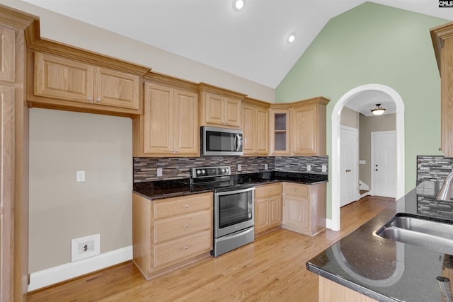 kitchen with decorative backsplash, appliances with stainless steel finishes, dark stone counters, and sink