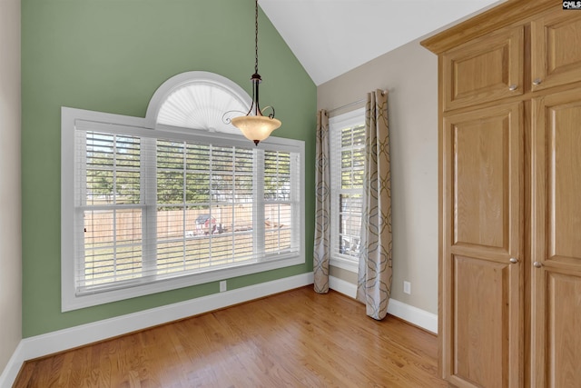 unfurnished dining area with plenty of natural light, high vaulted ceiling, and light hardwood / wood-style floors