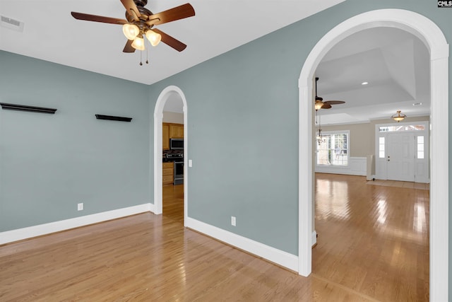 spare room featuring a tray ceiling, light hardwood / wood-style flooring, and ceiling fan with notable chandelier