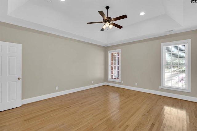 unfurnished room featuring light hardwood / wood-style floors, a raised ceiling, and ceiling fan