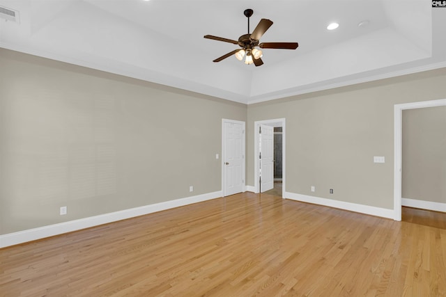 spare room featuring light hardwood / wood-style floors, ceiling fan, and a tray ceiling