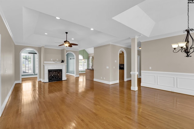 unfurnished living room with ceiling fan with notable chandelier, wood-type flooring, crown molding, and a tray ceiling