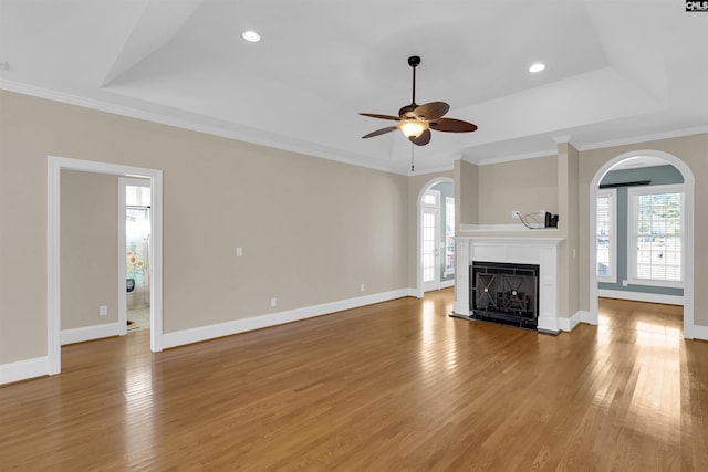 unfurnished living room with hardwood / wood-style floors, ceiling fan, crown molding, and a tray ceiling