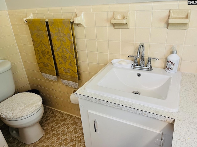 bathroom with vanity, tile walls, and toilet