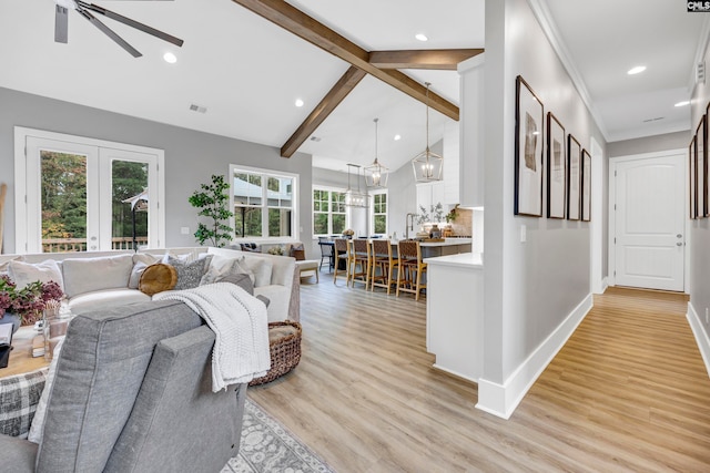 living room with plenty of natural light, light hardwood / wood-style floors, ceiling fan, and lofted ceiling with beams