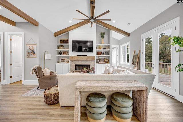 living room with vaulted ceiling with beams, a large fireplace, ceiling fan, and light hardwood / wood-style flooring