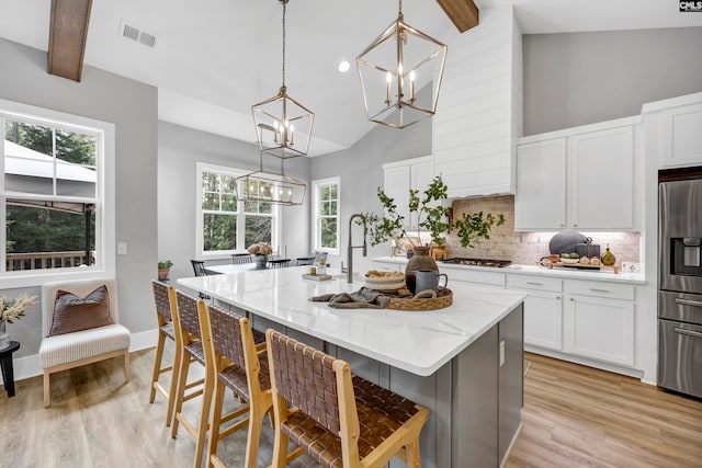 kitchen with pendant lighting, stainless steel appliances, a wealth of natural light, and an island with sink