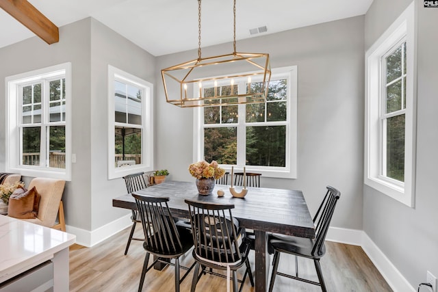 dining area featuring beam ceiling, light hardwood / wood-style flooring, a healthy amount of sunlight, and a notable chandelier