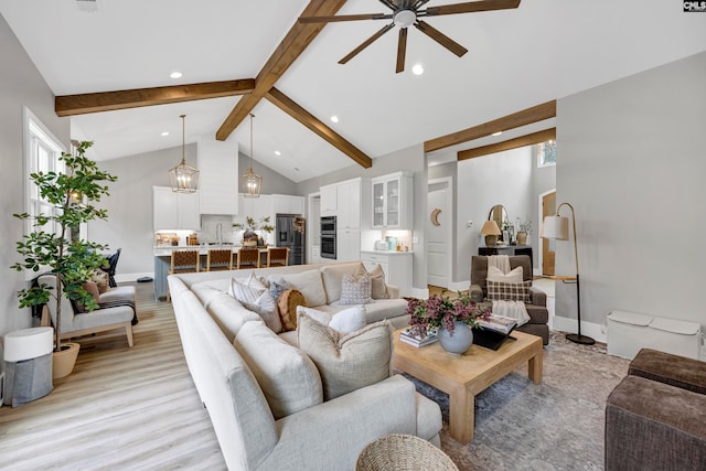 living room with beam ceiling, sink, high vaulted ceiling, light hardwood / wood-style floors, and ceiling fan with notable chandelier