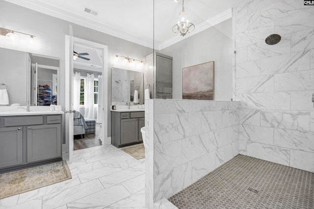 bathroom with ceiling fan with notable chandelier, tiled shower, crown molding, and vanity