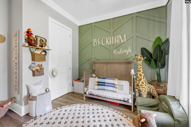 bedroom featuring a crib, dark hardwood / wood-style floors, and crown molding