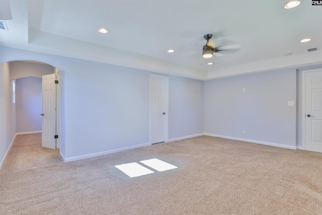 unfurnished room featuring light colored carpet, ceiling fan, and a tray ceiling