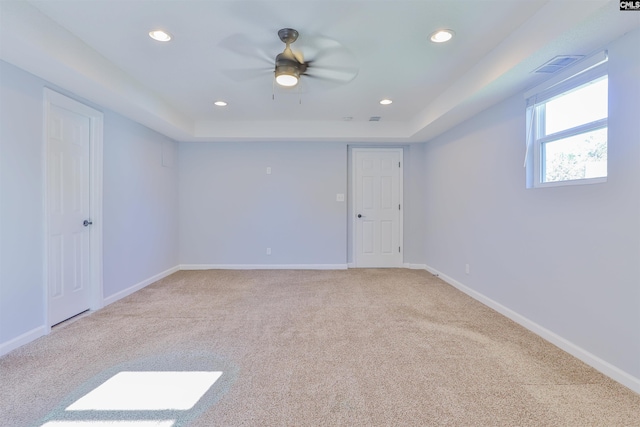 carpeted spare room with a tray ceiling and ceiling fan