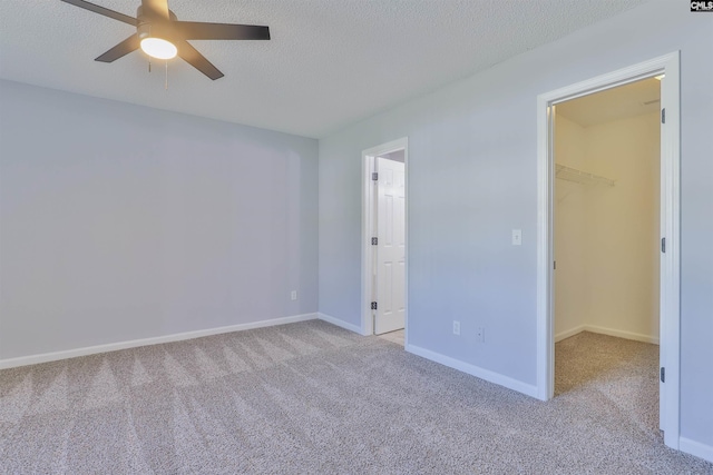 empty room featuring ceiling fan, light colored carpet, and a textured ceiling