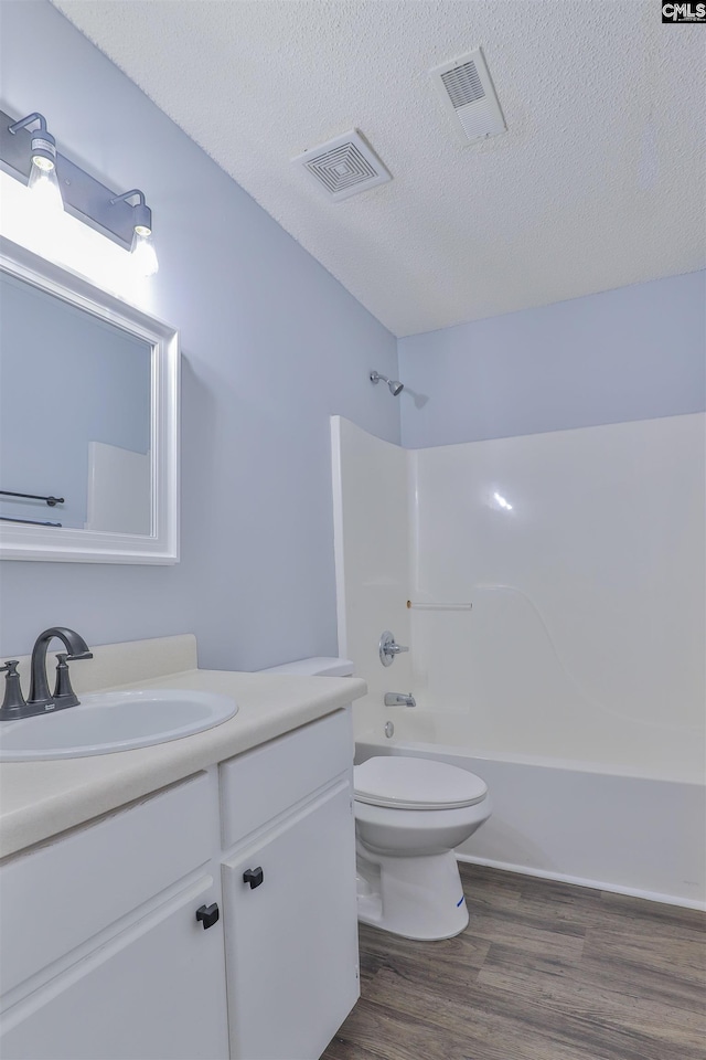 full bathroom featuring shower / bath combination, vanity, a textured ceiling, hardwood / wood-style flooring, and toilet