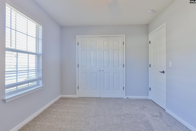 unfurnished bedroom with light carpet and a closet