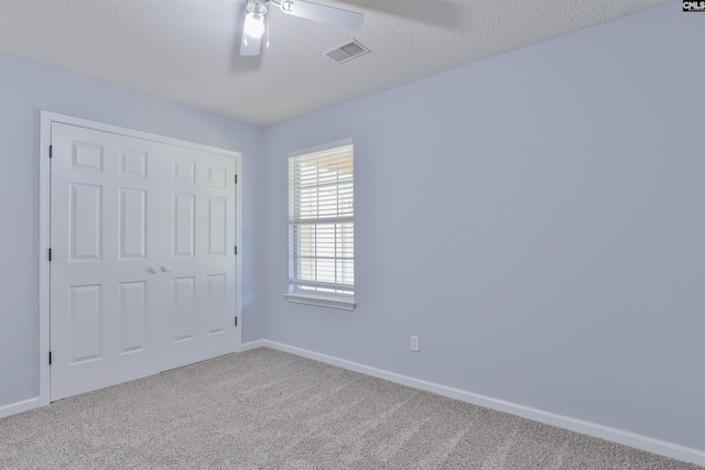 unfurnished bedroom featuring carpet, ceiling fan, a textured ceiling, and a closet