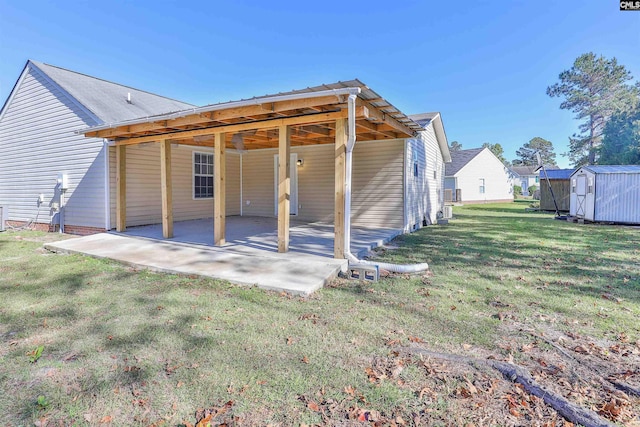 back of house featuring a yard, a patio, and a shed