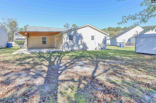 rear view of house with a patio area, a yard, and a storage shed