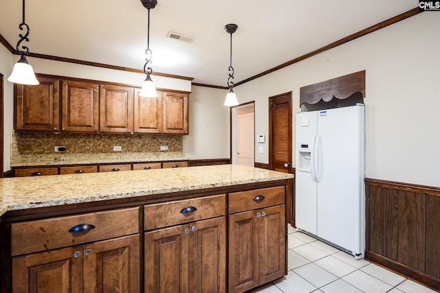 kitchen featuring white fridge with ice dispenser, light stone counters, crown molding, decorative light fixtures, and light tile patterned flooring