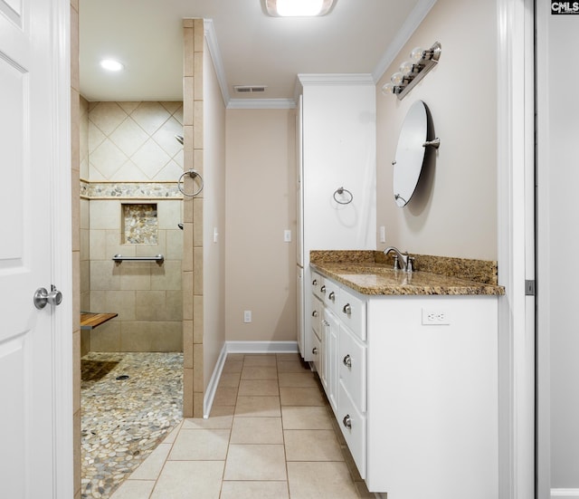 bathroom featuring tile patterned flooring, vanity, tiled shower, and ornamental molding