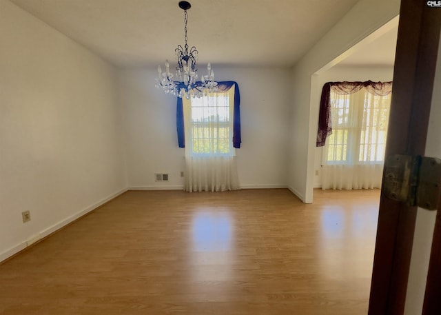 empty room with hardwood / wood-style flooring and a chandelier