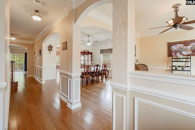 corridor with hardwood / wood-style flooring, ornate columns, and crown molding