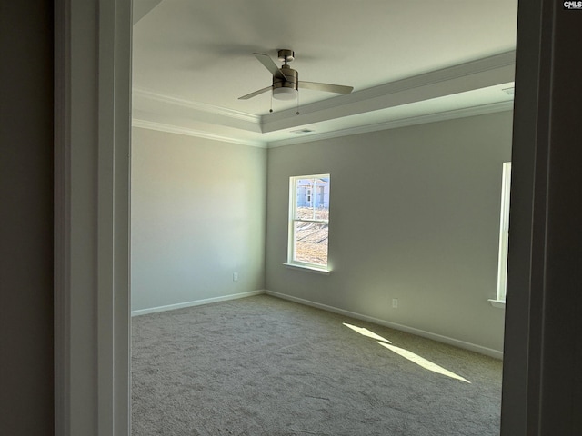 carpeted empty room with ceiling fan, ornamental molding, and a tray ceiling