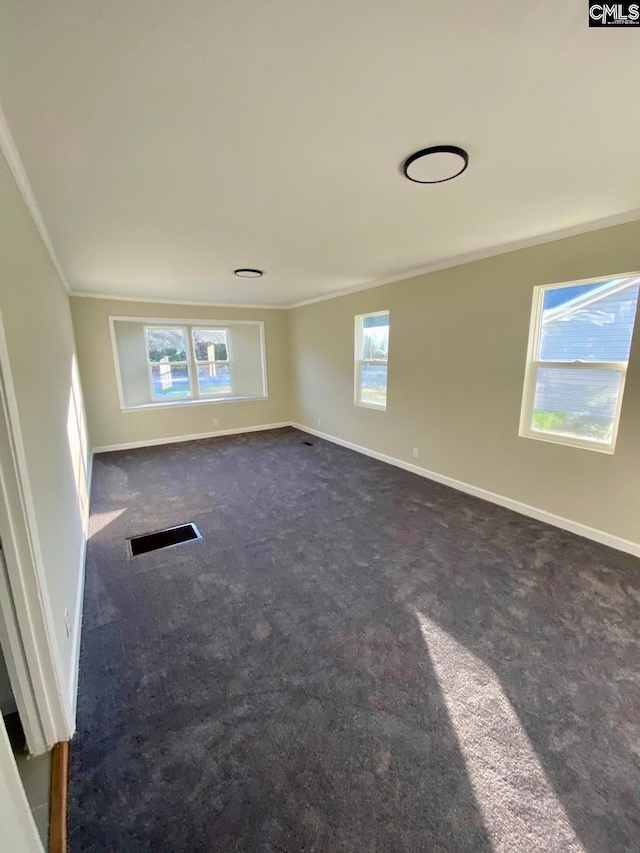 unfurnished room featuring dark colored carpet, plenty of natural light, and ornamental molding