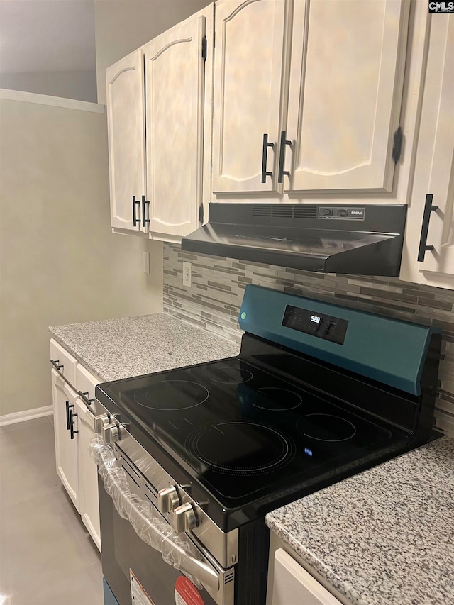 kitchen featuring electric range, white cabinets, range hood, and tasteful backsplash