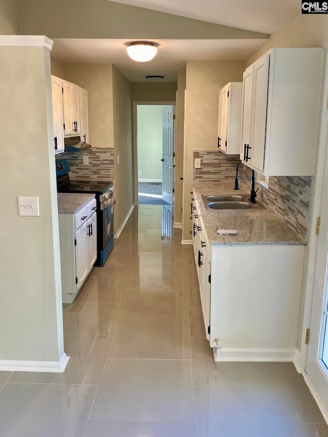 kitchen featuring electric range, sink, light stone countertops, decorative backsplash, and white cabinets