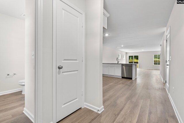 hall with light hardwood / wood-style flooring and sink