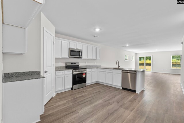 kitchen featuring light stone countertops, appliances with stainless steel finishes, light hardwood / wood-style floors, and white cabinetry