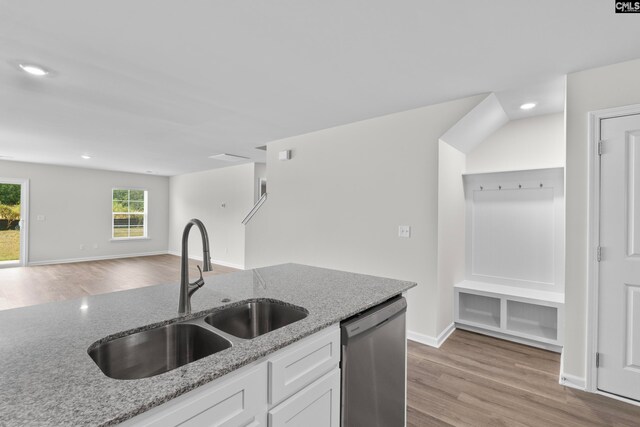 kitchen with light stone countertops, white cabinetry, stainless steel dishwasher, and sink