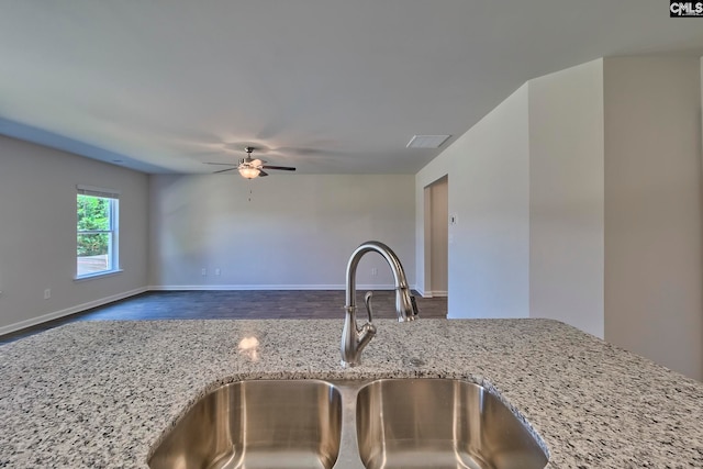 kitchen featuring ceiling fan, light stone counters, and sink